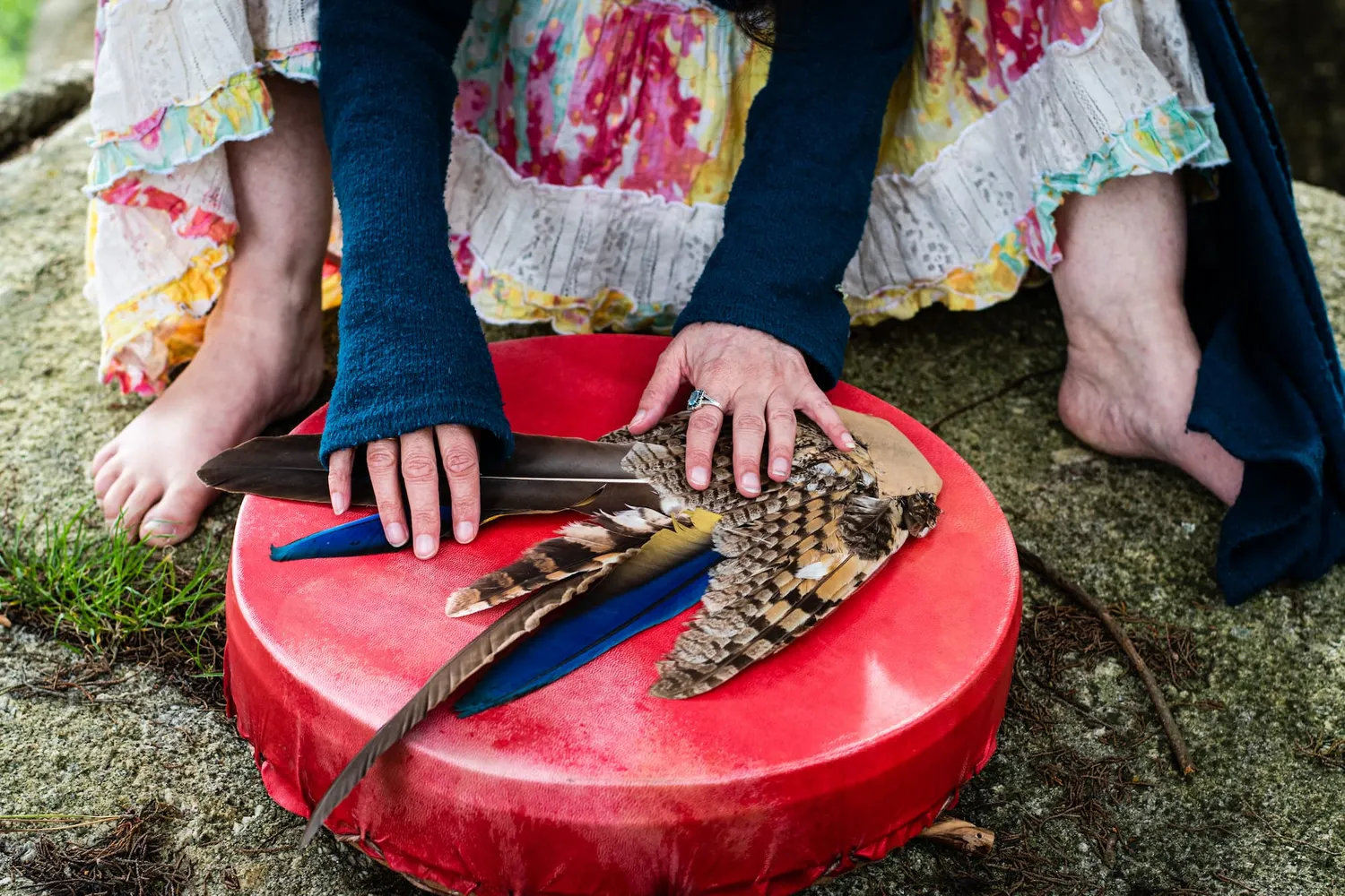 sur un tambour, deux mains posent des plumes.